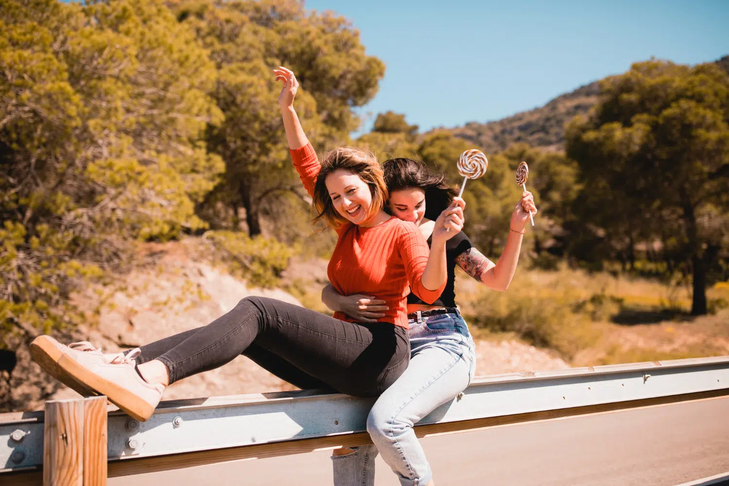 two-women-sitting-on-the-side-of-the-road-happy-with-their-hands-up.jpg